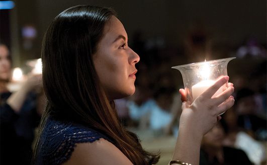 A student holding a candle in the dark.