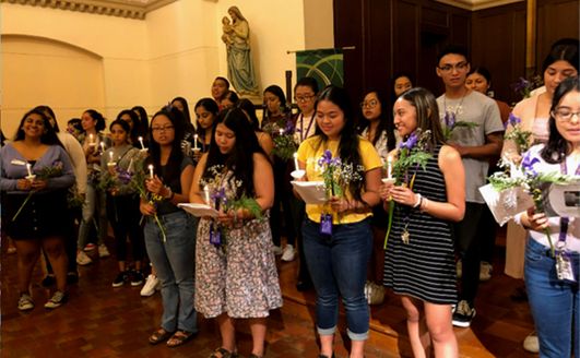 A large group of students taking part in a mass for welcoming a new class.