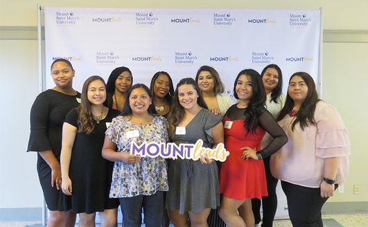 A group of people holding a Mountleads card standing in front of a white backdrop.