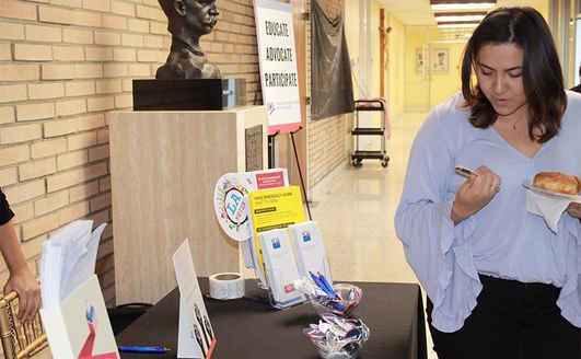 A student looking at a voting pin at a booth during a get out the vote event.