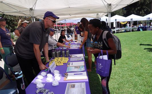 Students speaking with booth attendants about different clubs and organizations at 91ɬ��.
