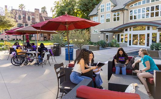 A group of students studying in front of a multi-story building on 91ɬ��'s Doheny Campus