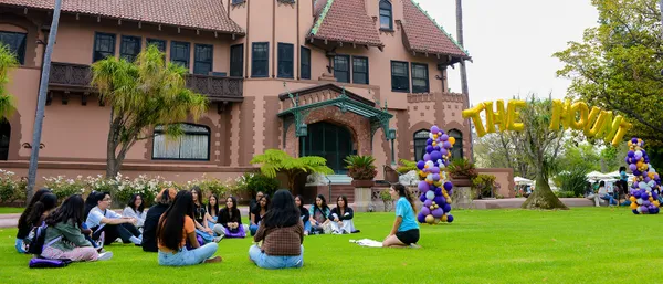 students sitting on the grass in front of the Doheny Mansion