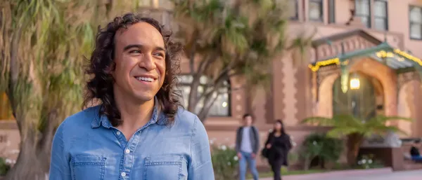 male student smiling with students in background walking on Doheny campus