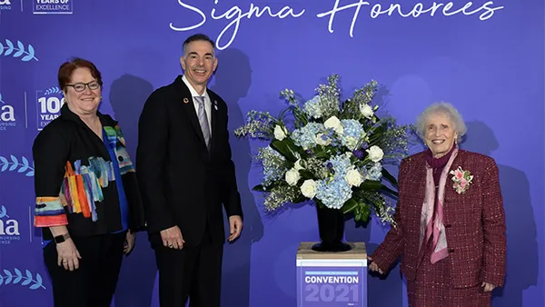 Three people standing on a stage to receive an award.