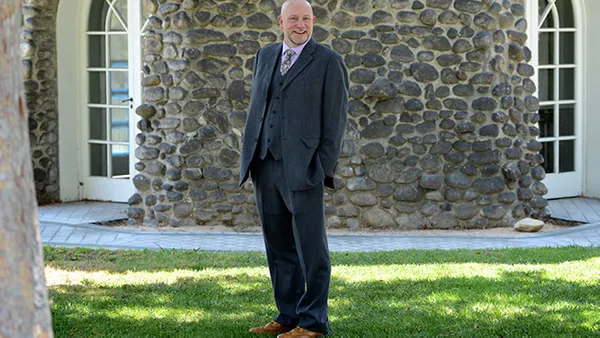 A picture of a man wearing a suit and smiling at the camera.