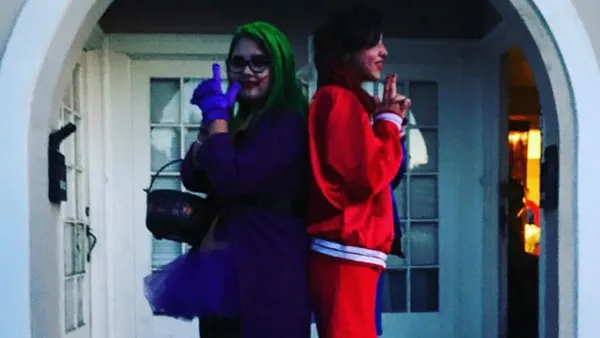 Two students standing back to back in halloween costumes.