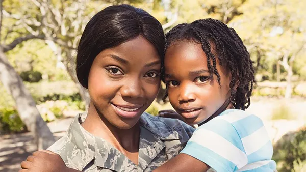 A woman holding a child and smiling at the camera.