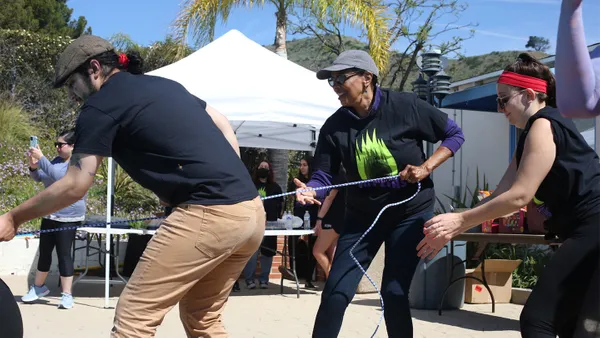 A popular event is the pool float pull, in which teammates pull one member across the length of the pool on a float -- but beware of tipping them over! In this photo, left to right, a friend of one of the students; Linda McMurdock, PhD, vice president of student affairs; and Alison Halpern, RD, CHES, associate director of wellness.