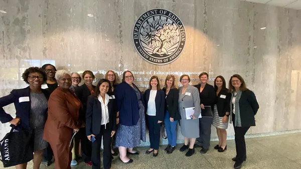 A group photo in front of the us department of education seal