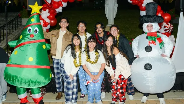 students smiling in front of a christmas backdrop