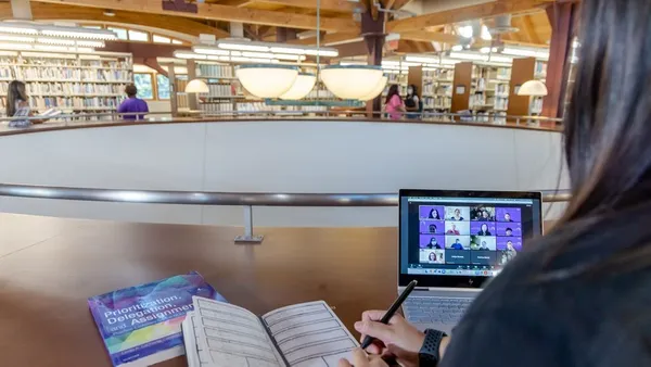 Mount student taking notes and tuning into a virtual presentation at the J. Thomas McCarthy Library.