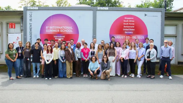 group of summer school students standing in a large group together in front of an outdoor wall