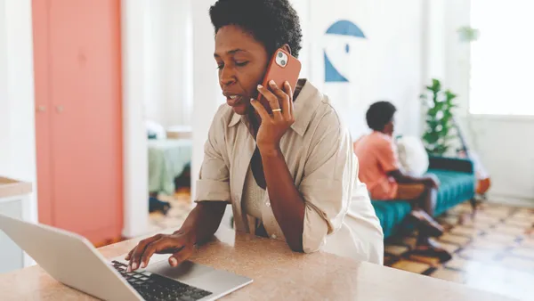 Woman looking at her laptop while talking on the phone.