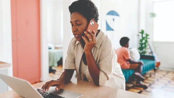 Woman looking at her laptop while talking on the phone.