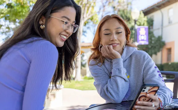 Two students looking at a phone at the Circle.
