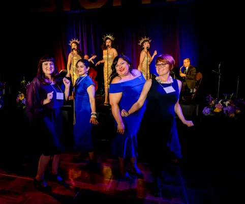 Alumnae dancing at the Homecoming Gala with singers in the background