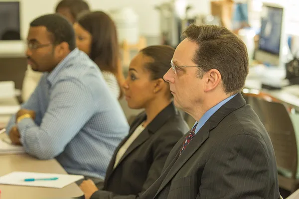 Man wearing a suit sitting in a classroom
