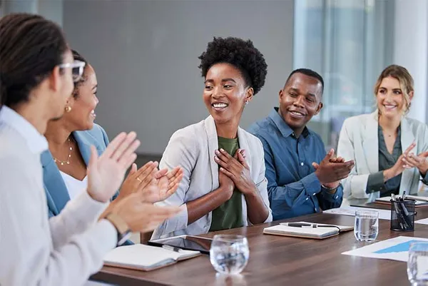 group of business professionals clapping for their colleague who is smiling
