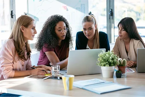 female business students working at a desk discussing over a laptop