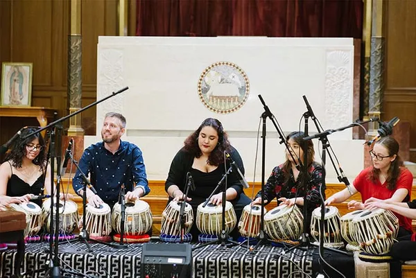 group of people sitting on the ground playing instruments