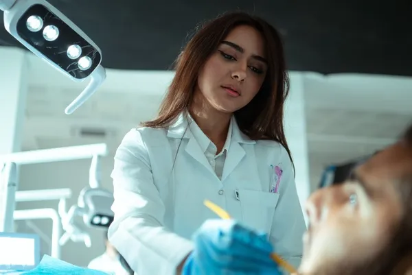 female dental student working on a male clients teeth