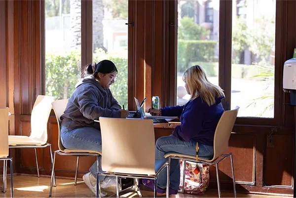 two students sitting at a table in a cafe on campus studying