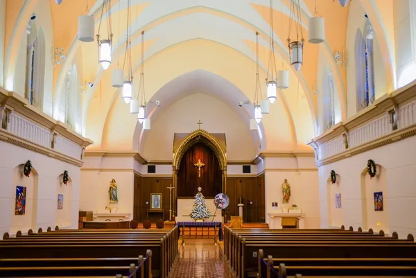 inside a chapel with empty wooden pews and an alter with red curtains