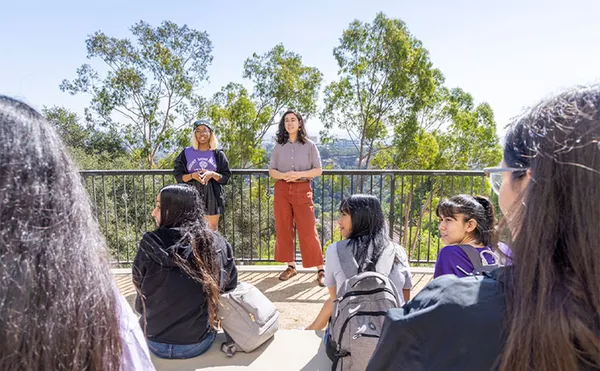 A group of students sitting on steps listening to two other students standing in front of them