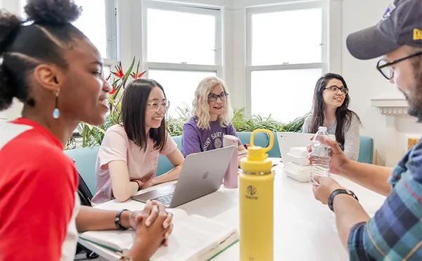 A group of five students studying around a table inside
