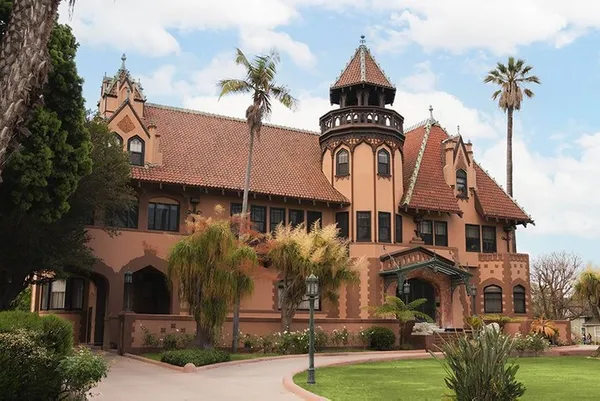 The front of the Doheny Mansion, including the green lawn and surrounding trees on the doheny campus
