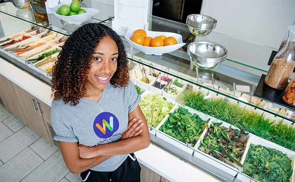 student standing at salad bar smiling with wellness shirt on