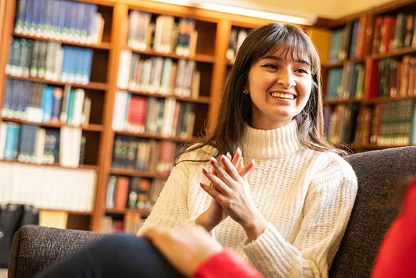 female student smiling discussing in library