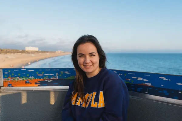 student with brunette hair smiling outdoors in a dark msmu sweater
