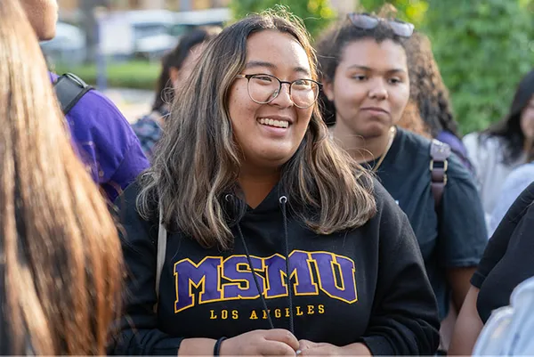 student smiling talking to someone with a MSMU sweater on