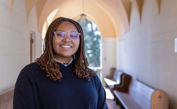 student with glasses smiling standing in corridor