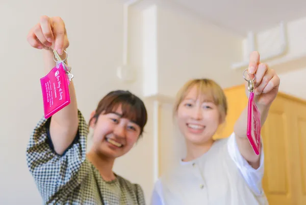 Two �鶹��ý��Ƶ international students holding keychains and smiling