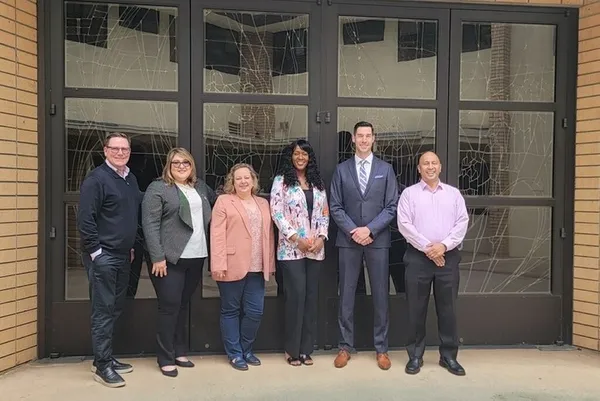 The MAPs Board of Directors smiling in front of glass windows
