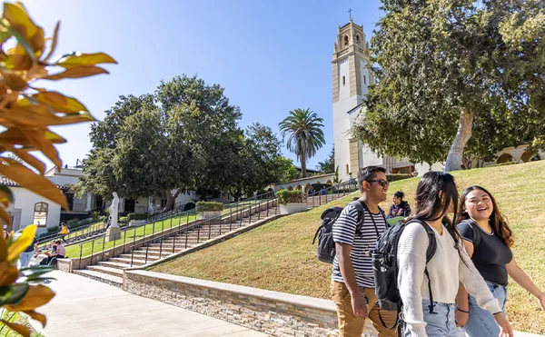 A group of students walking by with a bell tower in the background