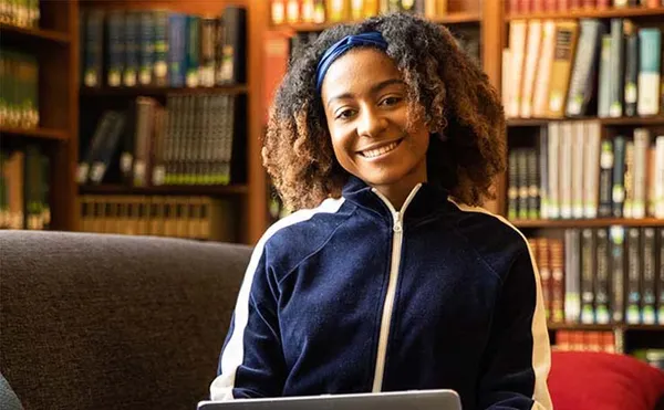 female student sitting in library smiling