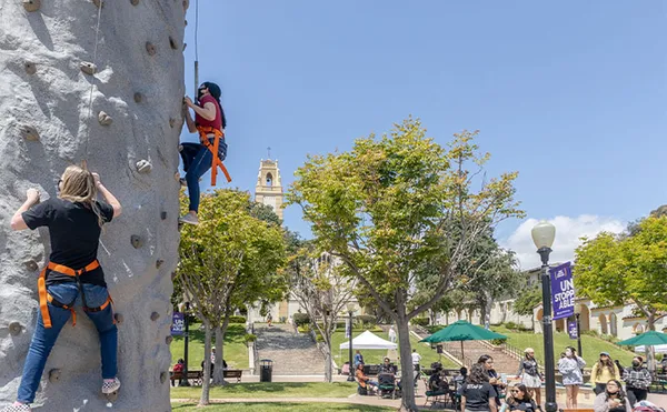 Two students climbing a rock climbing wall