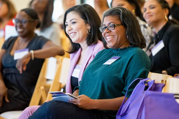 2 women sitting and laughing and listening to off-camera speaker