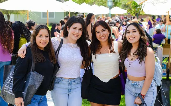 four students smiling on campus during an event to welcome new students