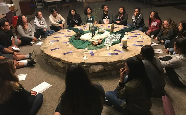 Students sitting on the floor in a circle around a low circular table