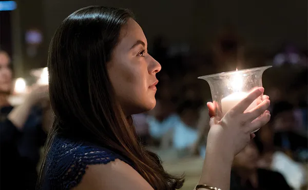 A student holding a candle in the dark.