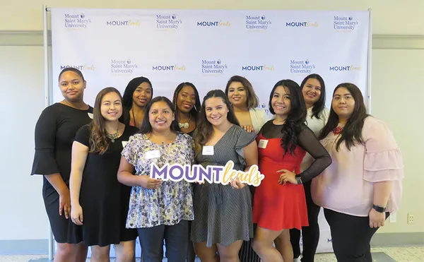 A group of people holding a Mountleads card standing in front of a white backdrop.