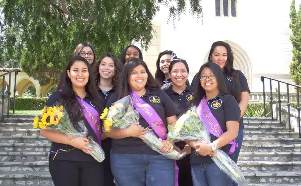 A group of people holding sunflowers and smiling in front of a chapel