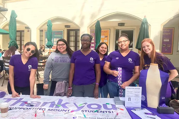 group of students at a table with a thank you signed sheet