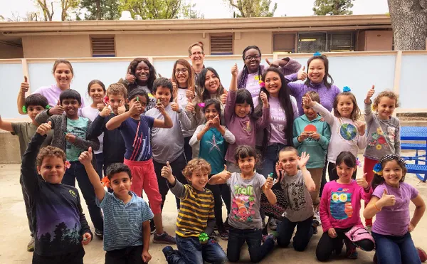 A large group of elementary school students giving the thumbs up with some ������ý WISH club members