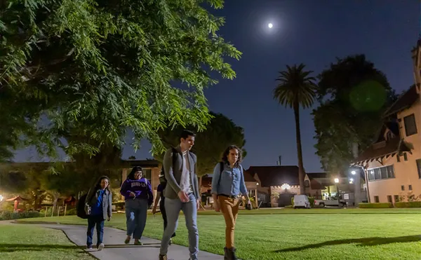 A small group of students talking across campus at night